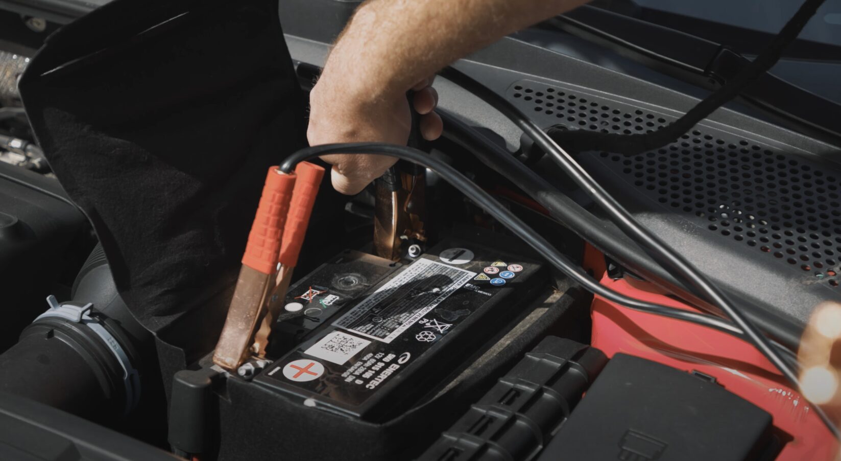 Roadside assistance technician jump starting a car battery